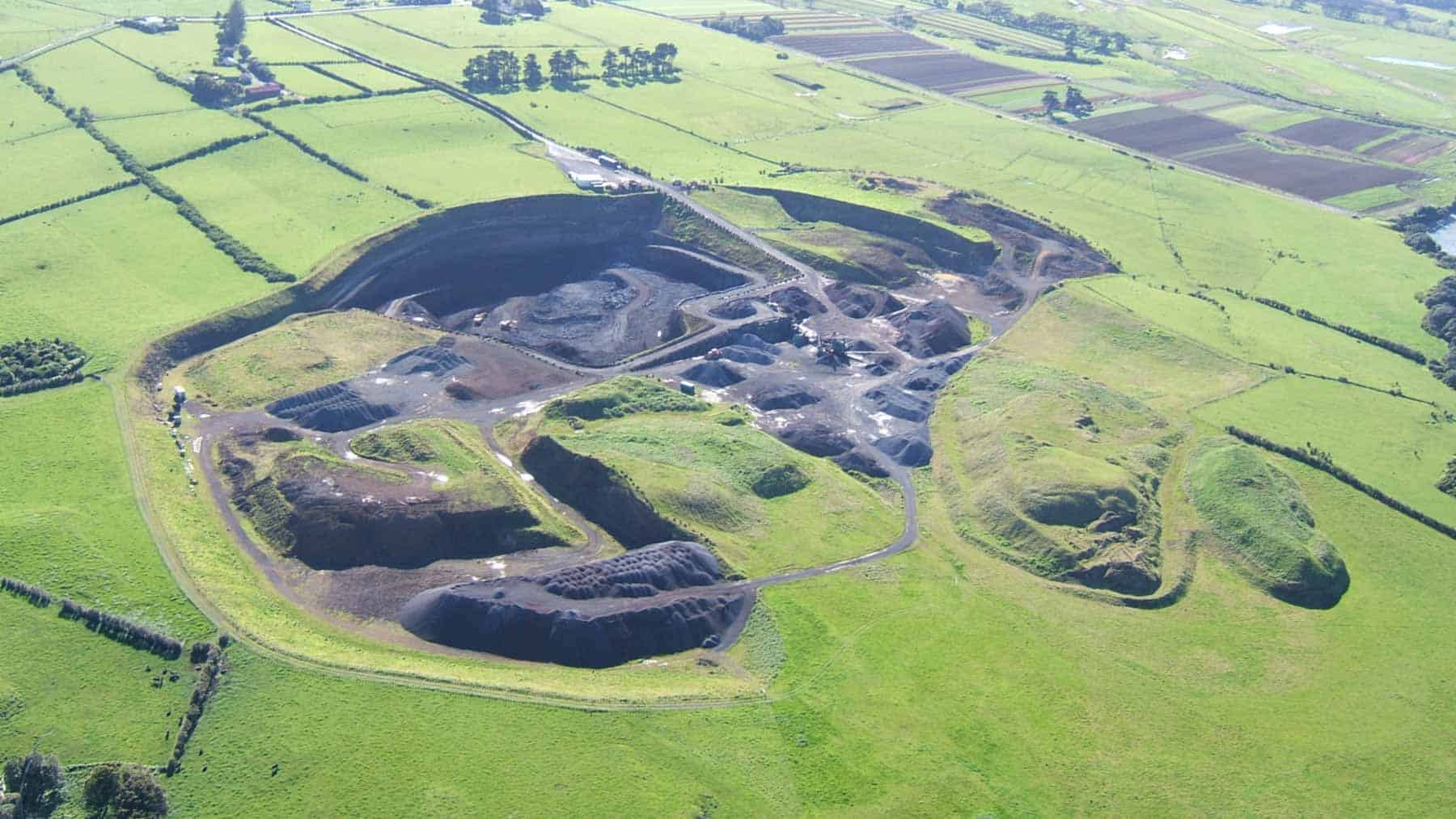 Aerial view of the quarry at Maungataketake / Elletts Mountain, showing excavated volcanic slopes, piles of scoria and surrounding green farmland.