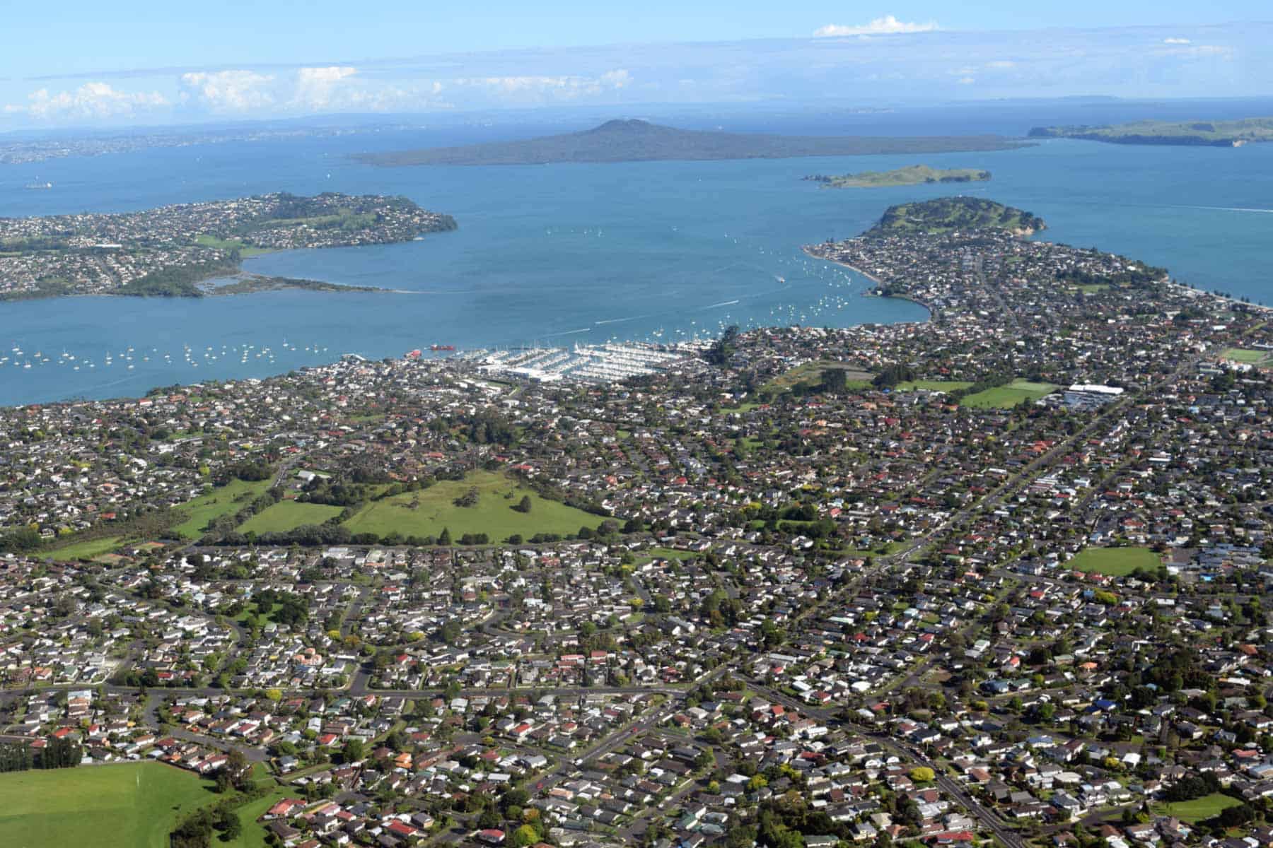 Aerial view of Ōhuiarangi / Pigeon Mountain and surrounding suburbs, with the Tāmaki Estuary and Rangitoto in the distance.