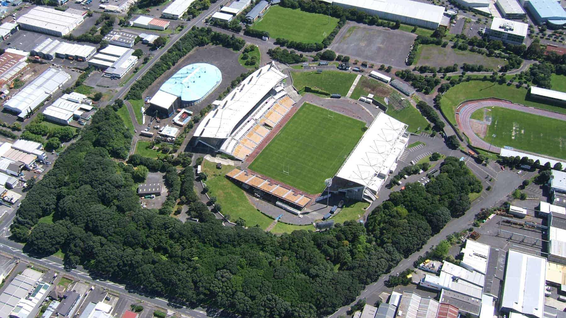 Aerial view of Mount Smart Stadium within the former Rarotonga / Mt Smart volcanic quarry, surrounded by trees and industrial buildings.