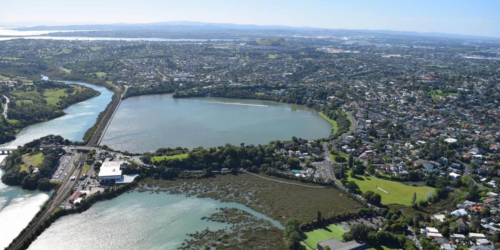Aerial view of Ōrākei Basin, a round tidal lagoon crossed by the railway